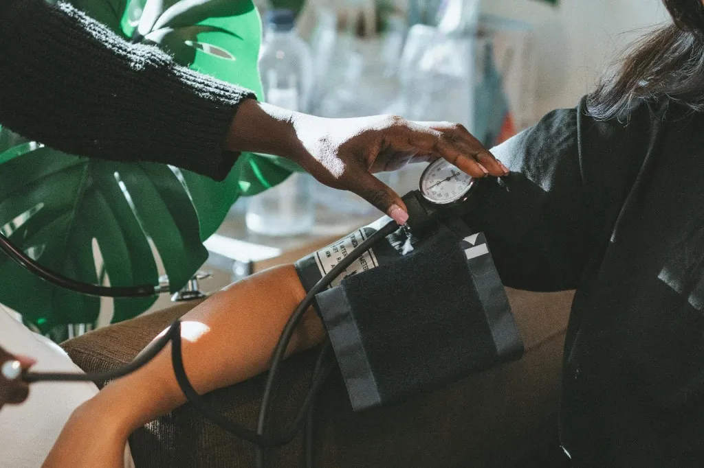 A nurse checking blood pressure with a manual cuff during a home wellness visit.