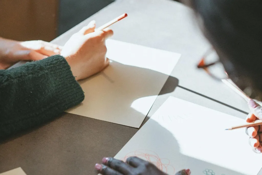 People drawing together at a table with coloured pencils during a support session.